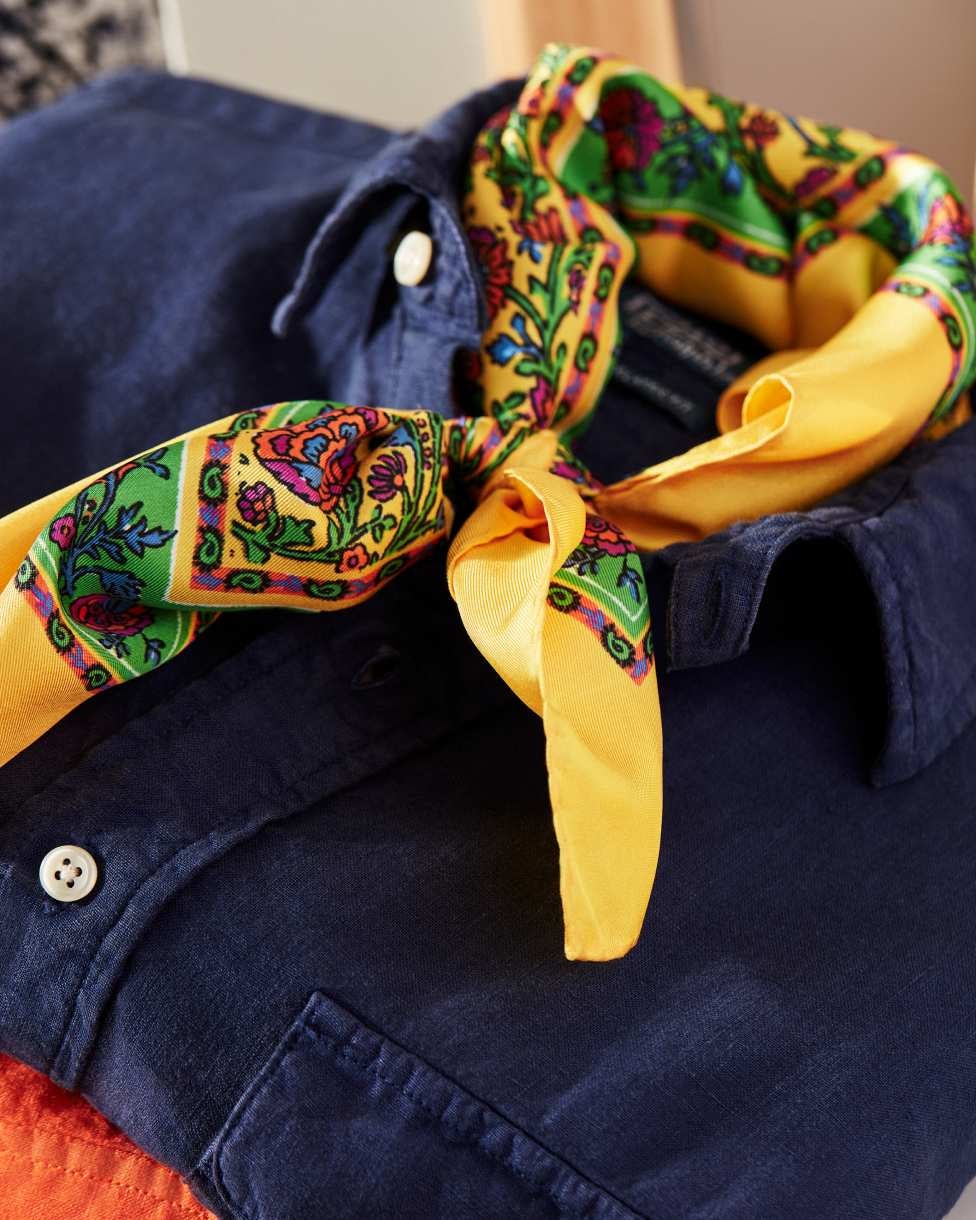 Folded navy blue linen button-down with yellow print scarf.