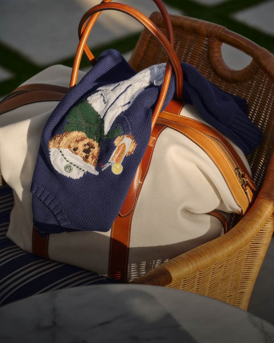 Navy sweater with Polo Bear knit at front on top of cream duffel in wicker basket.