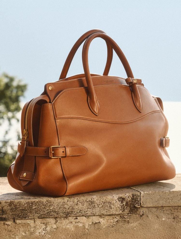 Brown leather duffel bag on stone ledge.