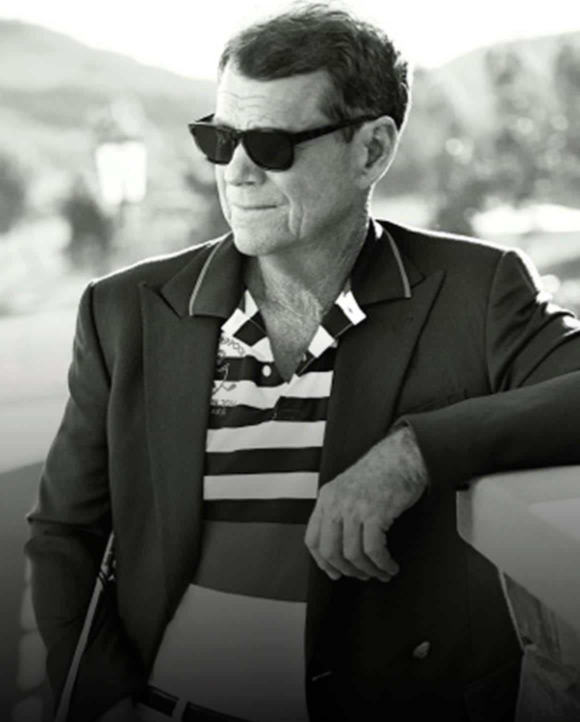 Black-and-white photo of Tom Watson in blazer and striped Polo shirt.